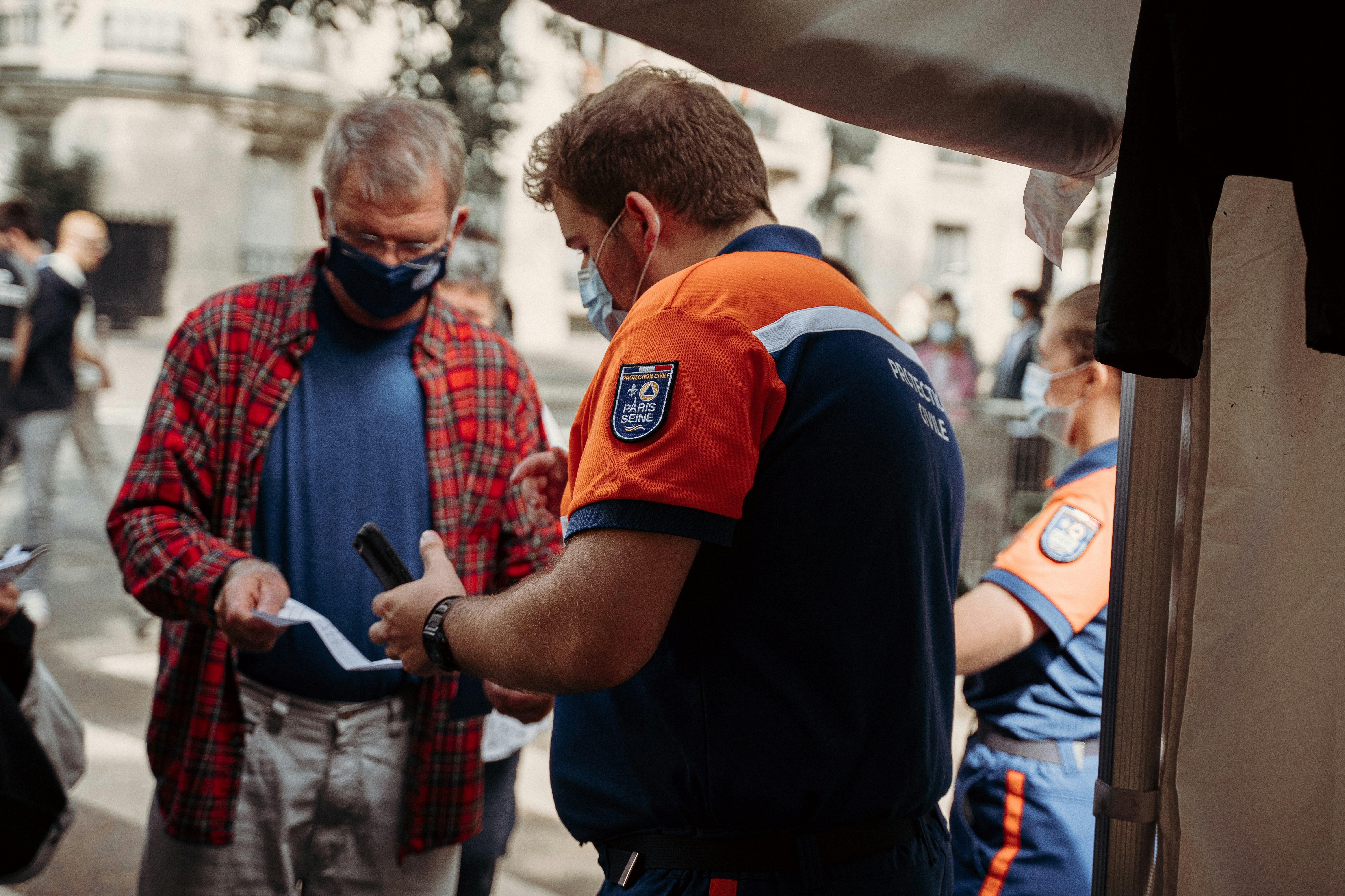 man in blue and orange polo shirt holding black smartphone